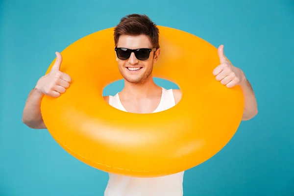 Chico en gafas de sol sosteniendo anillo inflable arjalá su cuello — Foto de Stock