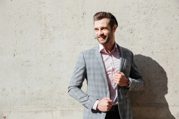 Portrait of a smiling young man in jacket posing and looking away — Stock Photo, Image