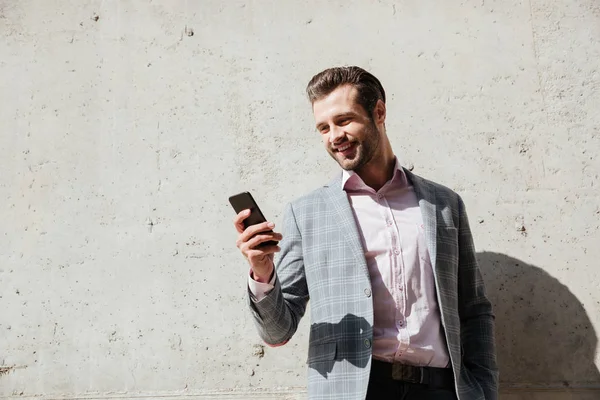 Retrato de un hombre feliz con chaqueta sosteniendo el teléfono móvil — Foto de Stock