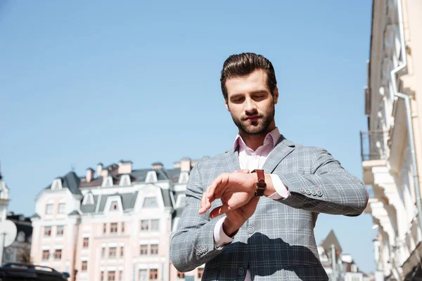 Handsome young man checking the time on his wrist watch — Stock Photo, Image