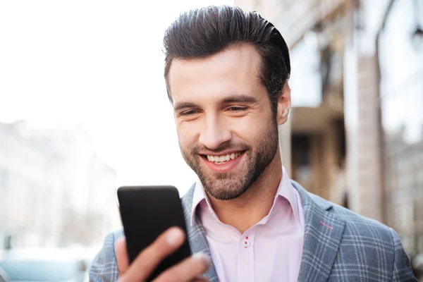Счастливый красивый мужчина в пиджаке смотрит на мобильный телефон — стоковое фото