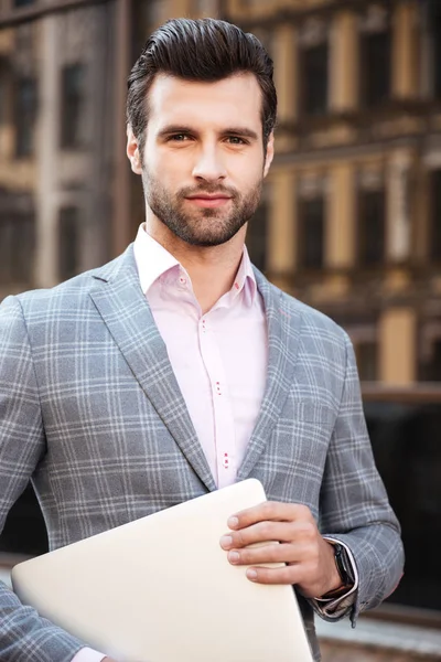 Porträt eines jungen, gut aussehenden Mannes in Jacke mit Laptop — Stockfoto