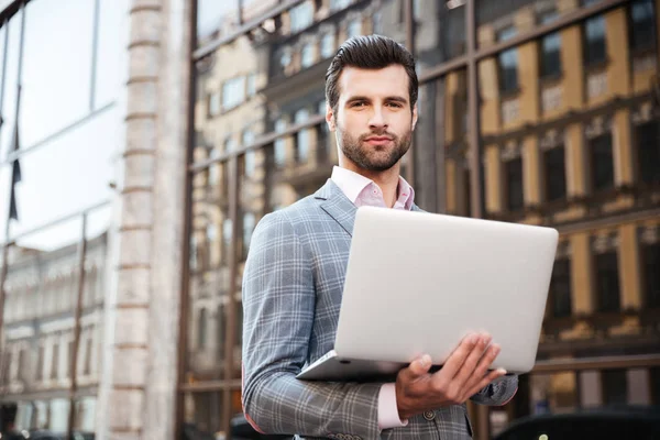 Retrato de um jovem bonito homem de jaqueta segurando laptop — Fotografia de Stock