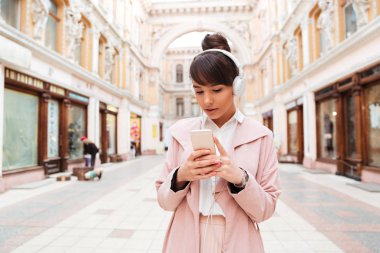 Kız pembe ceket dışında kulaklık ile müzik dinlemek