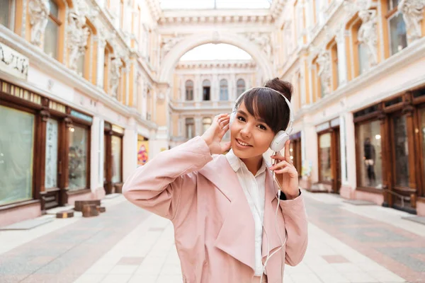 Menina ouvindo música com fones de ouvido em uma rua da cidade — Fotografia de Stock