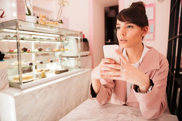 Thoughtful young woman holding mobile phone — Stock Photo, Image