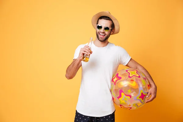 Joven alegre sosteniendo cerveza y pelota de playa . — Foto de Stock