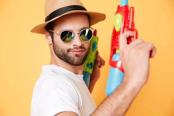 Serious young man holding toy water guns. — Stock Photo, Image