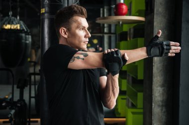 Ciddi genç sporcu spor salonunda germe egzersizleri yapmak.