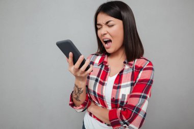 Kızgın genç Asyalı kadın telefonu kullanarak izole.