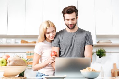 genç bir çift için yemek tarifi bakmak için dizüstü bilgisayar kullanarak