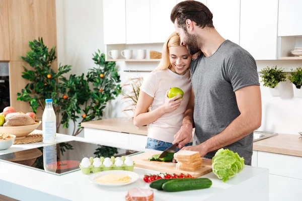 Усміхнена молода любляча пара стоїть на кухні і готує — стокове фото