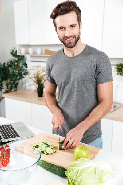 Улыбающийся человек готовит овощной салат у современного парня — стоковое фото