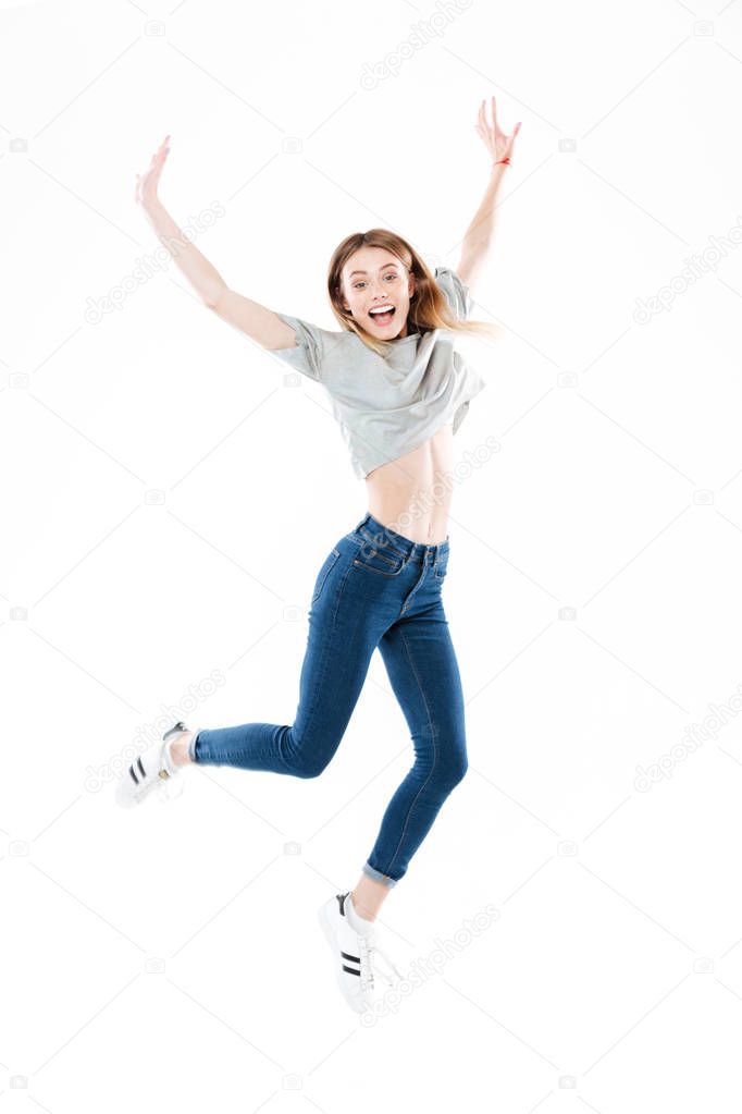 Portrait of a happy pretty girl jumping with hands raised