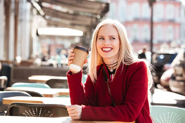 Sonriente joven mujer caucásica sentada en la cafetería al aire libre —  Fotos de Stock