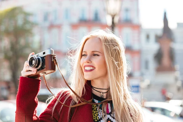 Flot ung kaukasisk kvinde går udendørs med kameraet - Stock-foto