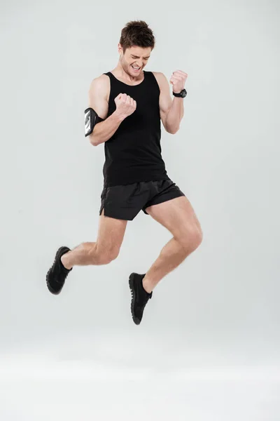 Pohledný mladý sportovec skákání zobrazeno vítěz gesto — Stock fotografie
