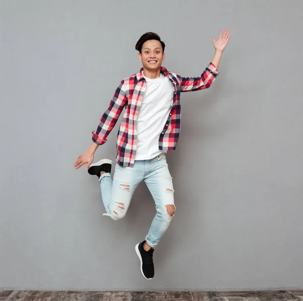 Jumping young asian man over grey background. — Stock Photo, Image