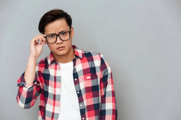 Verwirrter junger asiatischer Mann mit grauem Hintergrund — Stockfoto