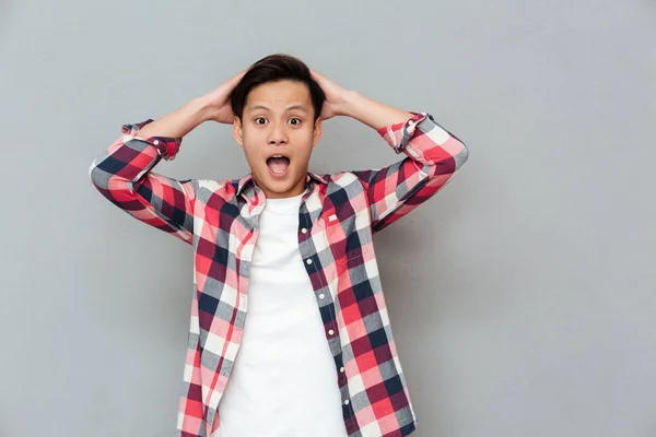 Screaming shocked young asian man over grey background — Stock Photo, Image