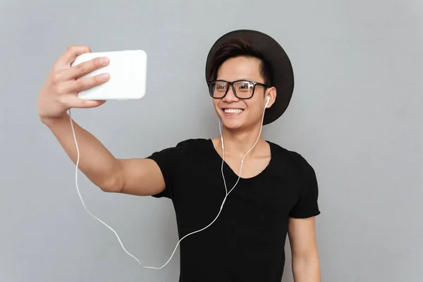 Sonriendo joven asiático hombre escuchar música y hacer selfie — Foto de Stock