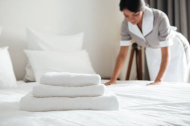 Genç otel hizmetçisi yastık yatak üzerinde ayarlama