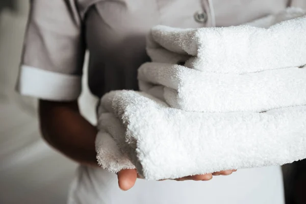 Close up of a young maid holding folded towels — Stock Photo, Image