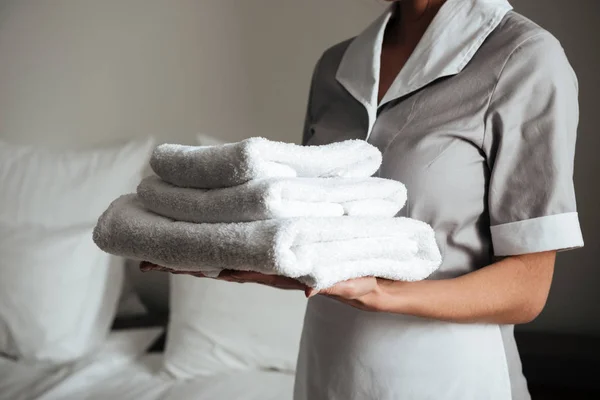 Νεαρή καθαρίστρια κρατώντας διπλωμένες πετσέτες — Φωτογραφία Αρχείου