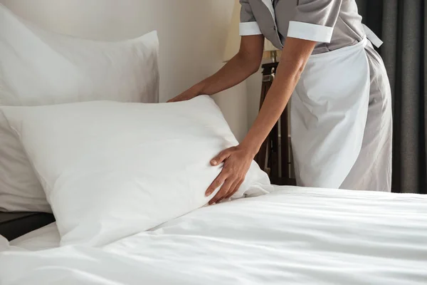 Imagem cortada de uma camareira fazendo cama no quarto do hotel — Fotografia de Stock