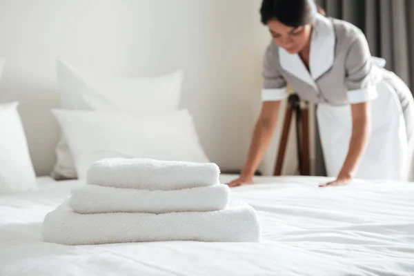 Young hotel maid setting up pillow on bed — Stock Photo, Image