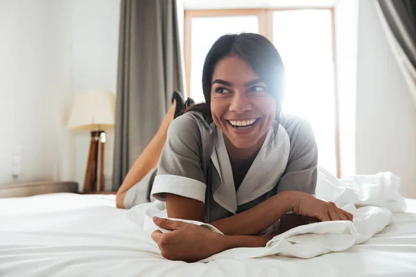 Sorrindo empregada do hotel deitada em uma cama — Fotografia de Stock
