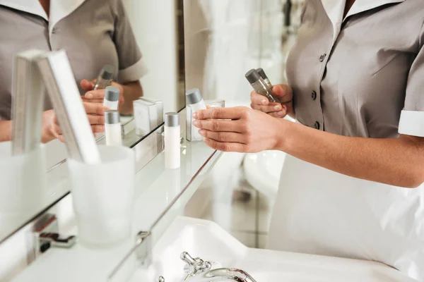 Young hotel maid putting bath accessories in a bathroom — Stock Photo, Image