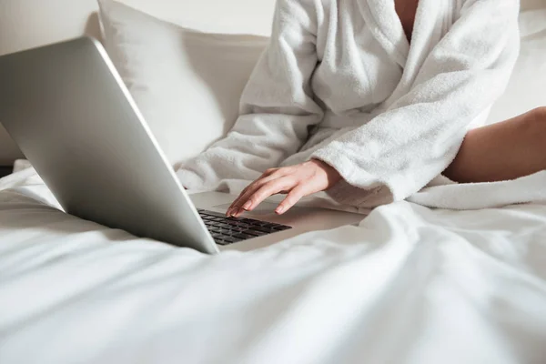 Przycięte zdjęcie kobiety w szlafrok na łóżku i komputera przenośnego — Zdjęcie stockowe