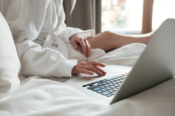 Immagine ritagliata di una donna in accappatoio sul letto e utilizzando il computer portatile — Foto Stock