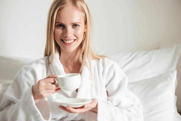 Щаслива усміхнена жінка в халаті тримає чашку кави — стокове фото