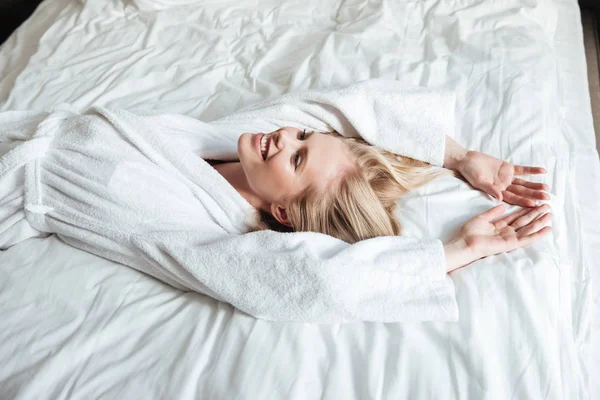 Усміхнена жінка в халаті відпочиває на ліжку — стокове фото