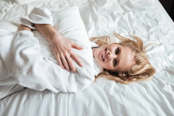 Mujer joven feliz en albornoz acostado en la cama — Foto de Stock