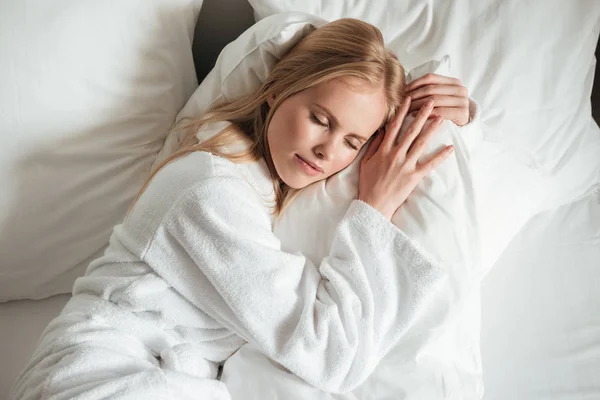 Preciosa joven en albornoz durmiendo en la cama —  Fotos de Stock