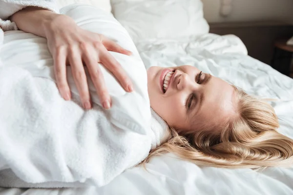 Mujer rubia bonita en albornoz descansando en la cama — Foto de Stock