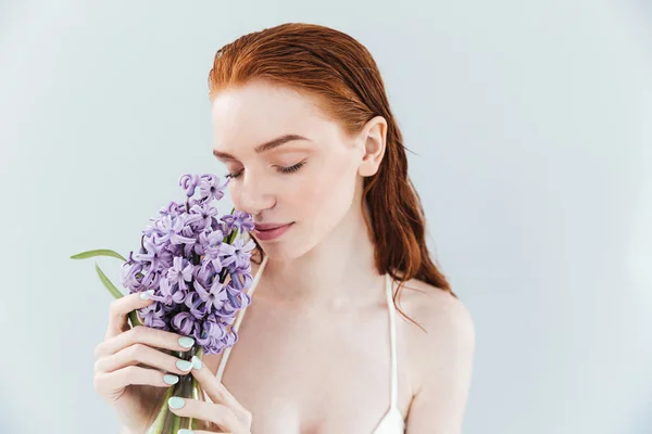 Close up portrait of a ginger woman smelling hyacinth flowers — Stock Photo, Image