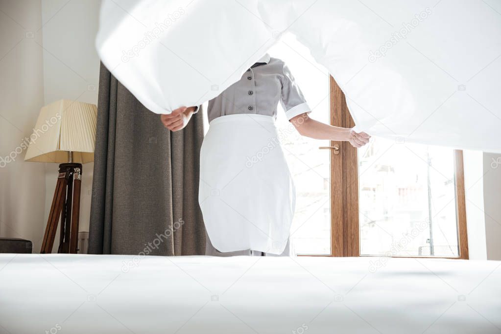Cropped image of a hotel maid changing bed sheet