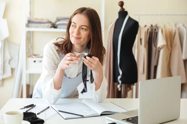 Mujer costurera que trabaja con el ordenador portátil y telas —  Fotos de Stock