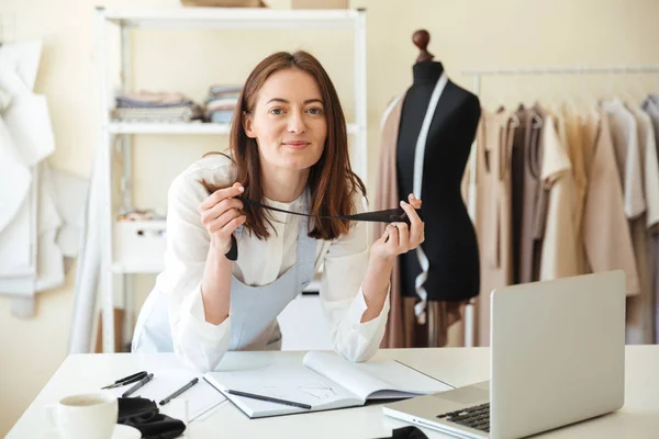 Mujer costurera que trabaja con el ordenador portátil y telas —  Fotos de Stock