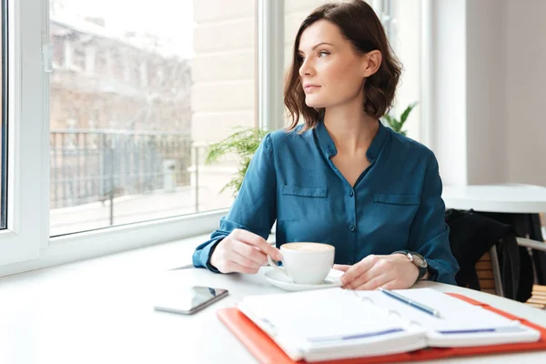 Attractive woman sitting at the cafe table and drinking coffee — Stock Photo, Image