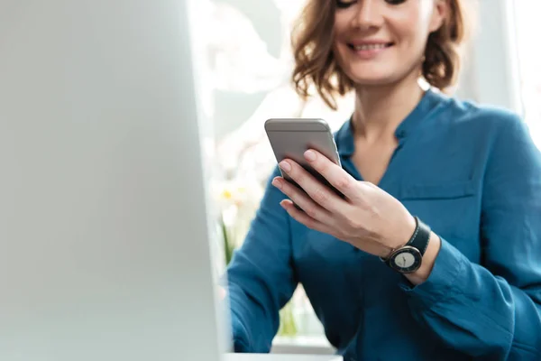 Cropped image of a smiling young woman holding mobile phone — Stock Photo, Image