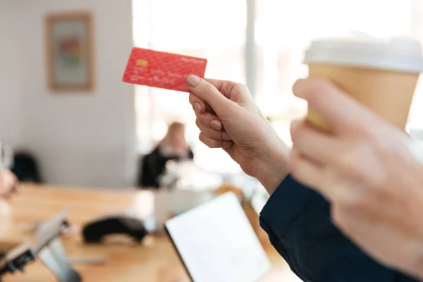 Image recadrée d'une femme tenant une carte de crédit et un café . — Photo