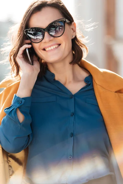 Счастливая красивая женщина в солнечных очках разговаривает по мобильному телефону — стоковое фото