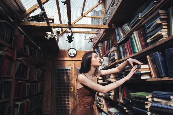 Junge Frau steht in Bibliothek — Stockfoto
