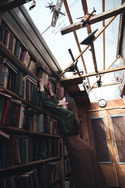 Mladá žena hledající knihu v knihovně — Stock fotografie