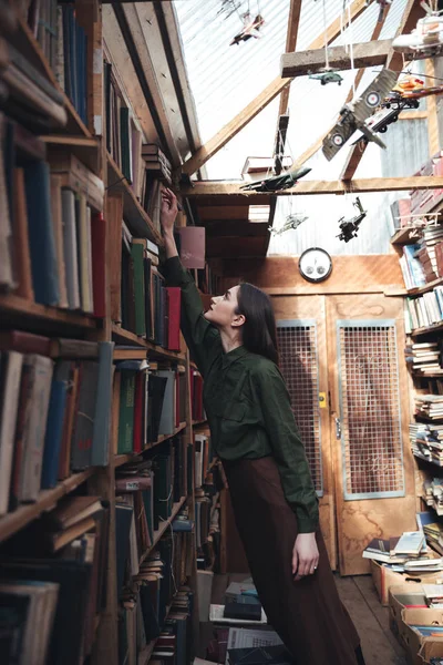 Seitenansicht einer Frau, die Buch aus dem Regal nimmt — Stockfoto